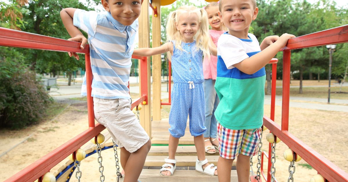 Four preschoolers smiling on the outdoor playground