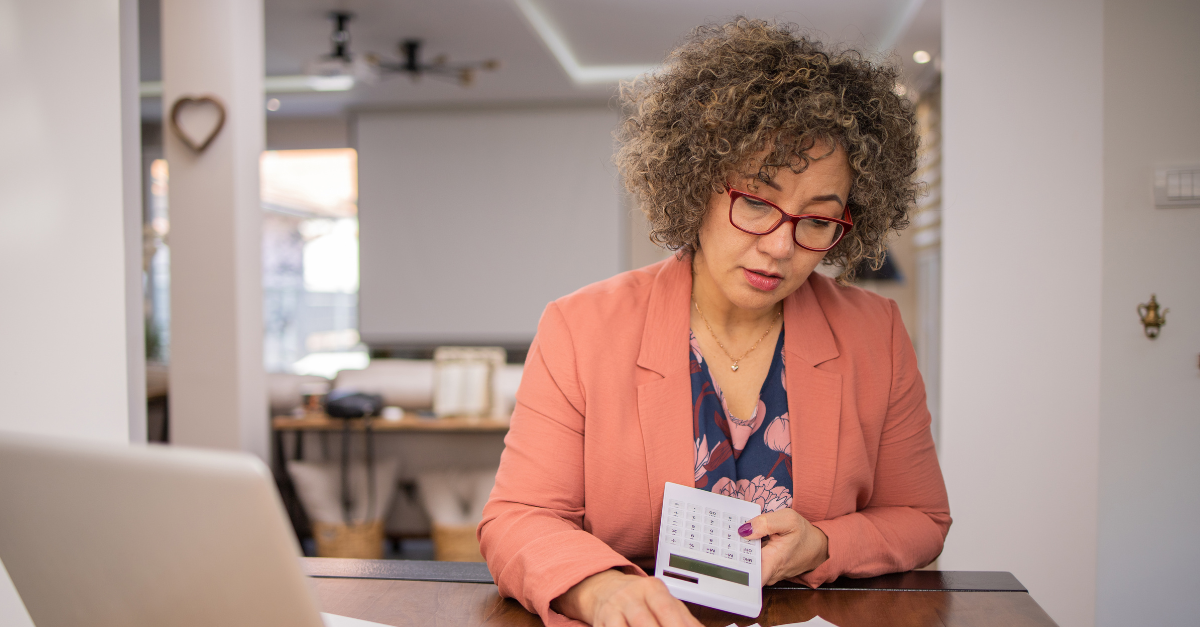 Childcare director sitting at her computer with a calculator as she reviews tax receipts.