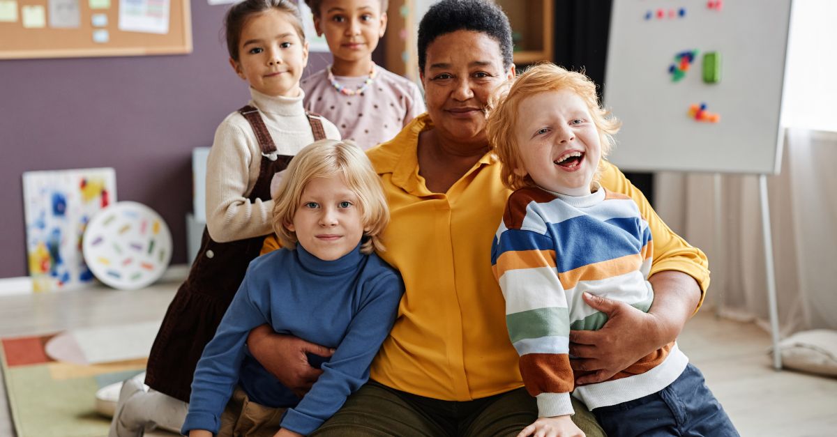 Early childhood educator with a group of preschoolers smiling at the camera