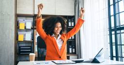 A new childcare owner sitting at their computer and celebrating as they accomplish steps to open their new center